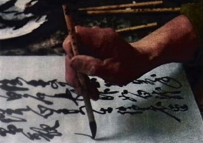 La mano del calligrafo: il pennello è impugnato alto e la mano non è appoggiata sul piano di scrittura.